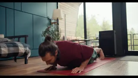 A happy brunette guy in a red T-shirt is tired of doing push-ups and lay down on a red mat to rest Fitness classes at home