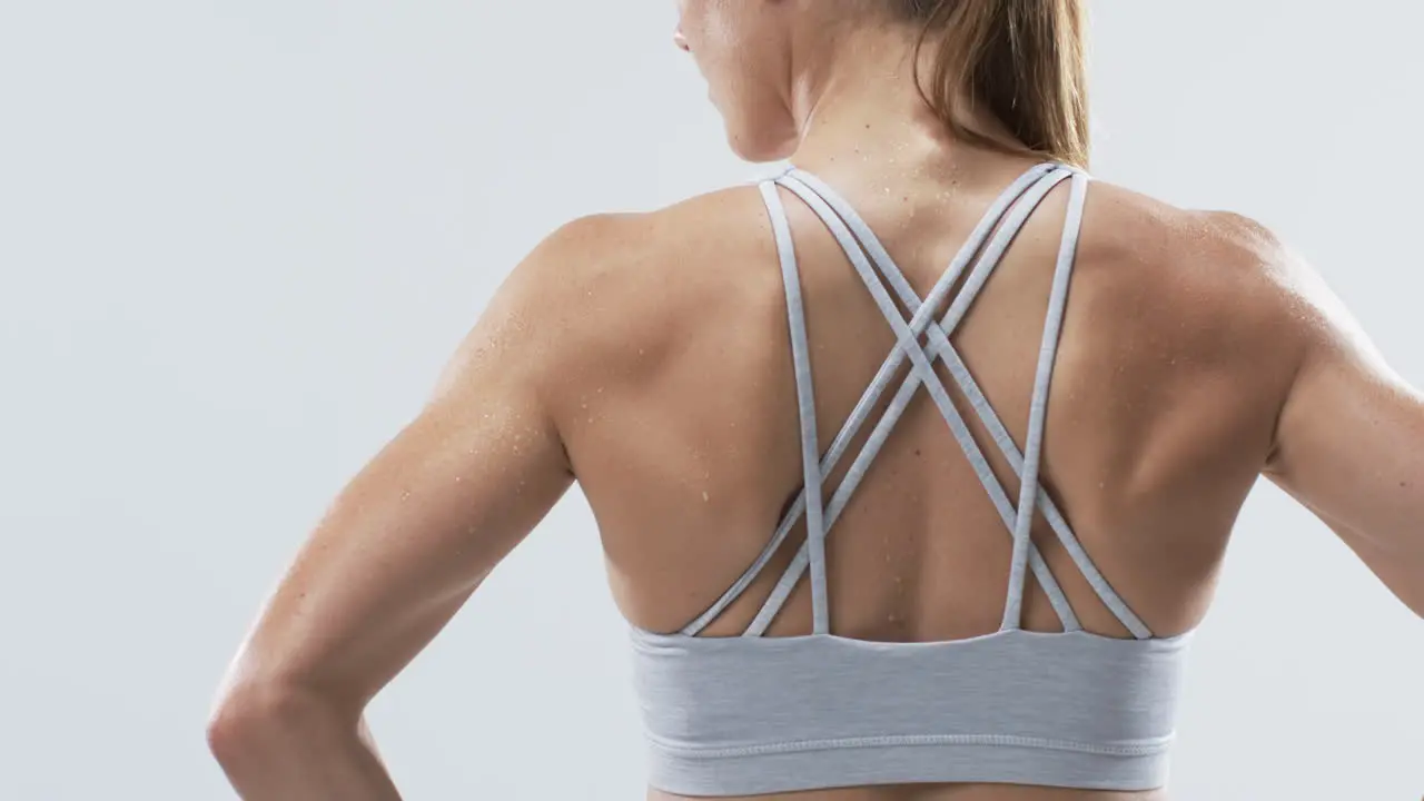 Close-up of a young Caucasian woman athlete's back showcasing sportswear on a white background