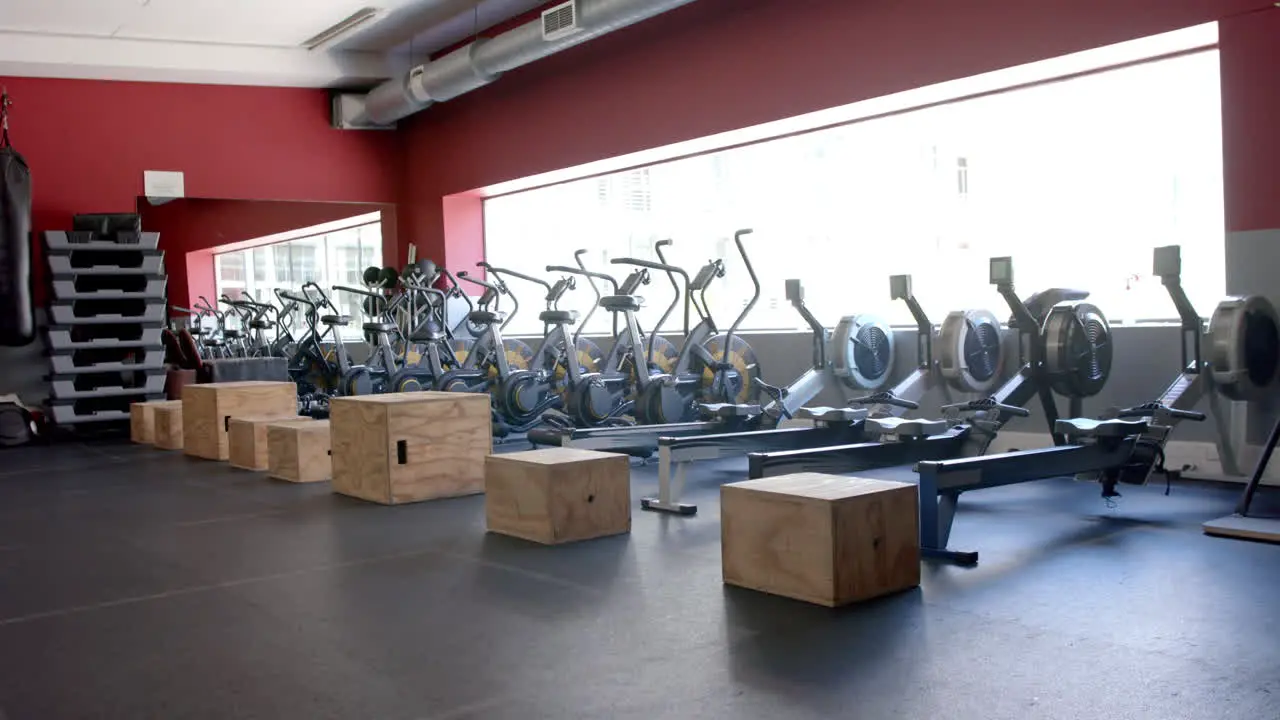 A modern gym with rows of stationary bikes and rowing machines