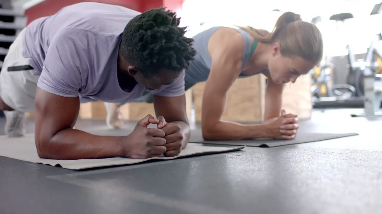 Fit African American man and young Caucasian woman exercising at the gym