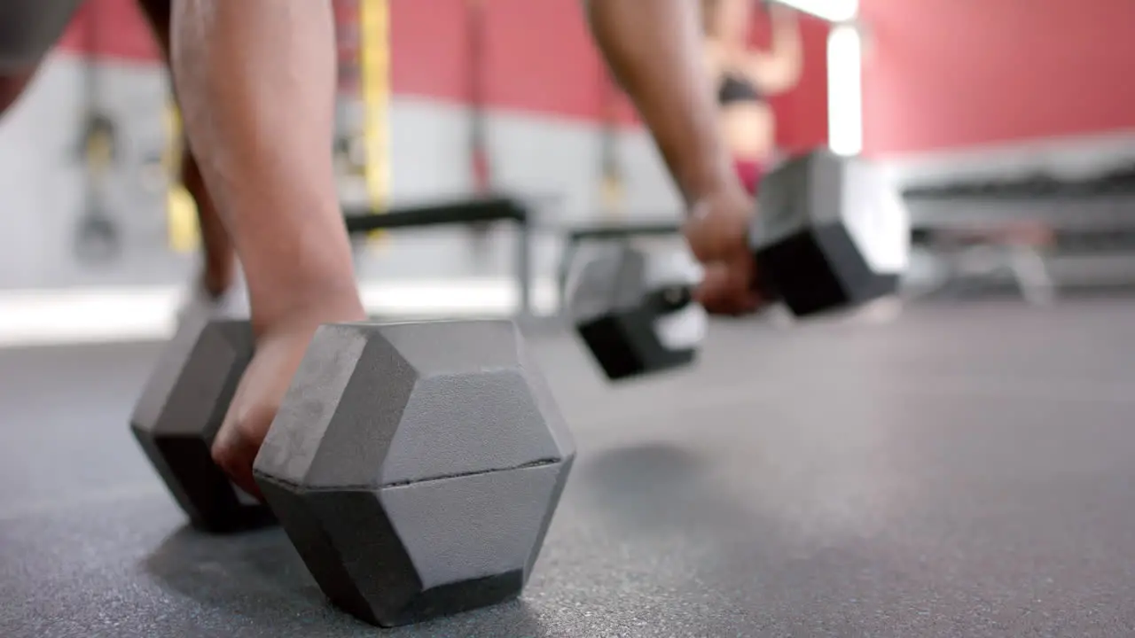 Close-up of a person lifting heavy dumbbells at the gym