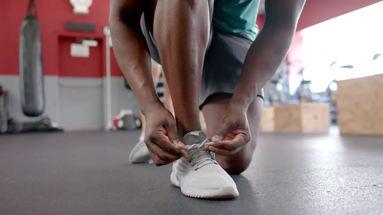 African American man ties his sneakers at the gym