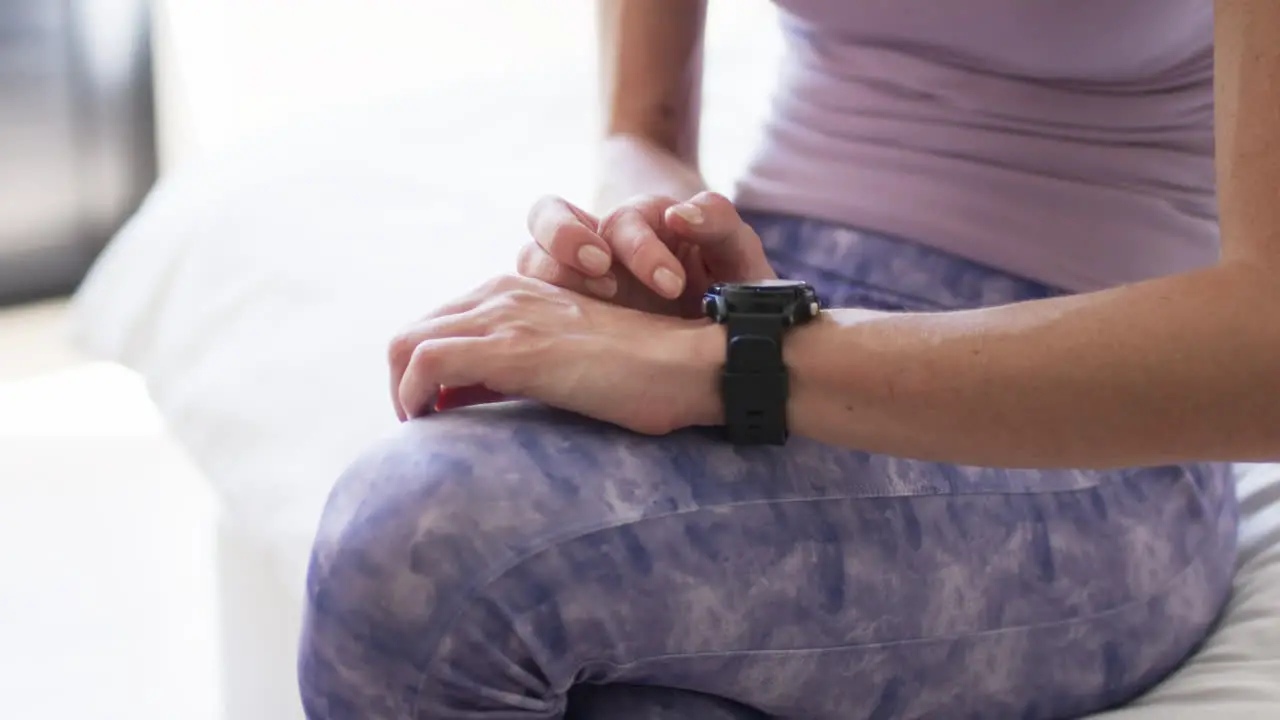 Middle-aged Caucasian woman checks her smartwatch during a workout at home