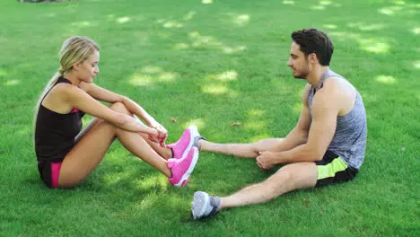 Sport couple resting on grass after outdoor workout Young man and woman