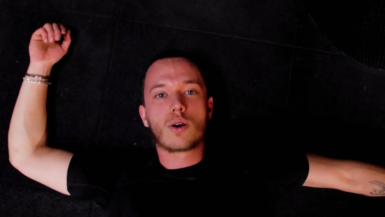 floor shot from the ceiling of a young athletic Caucasian man lying on the floor completely exhausted after a strenuous workout