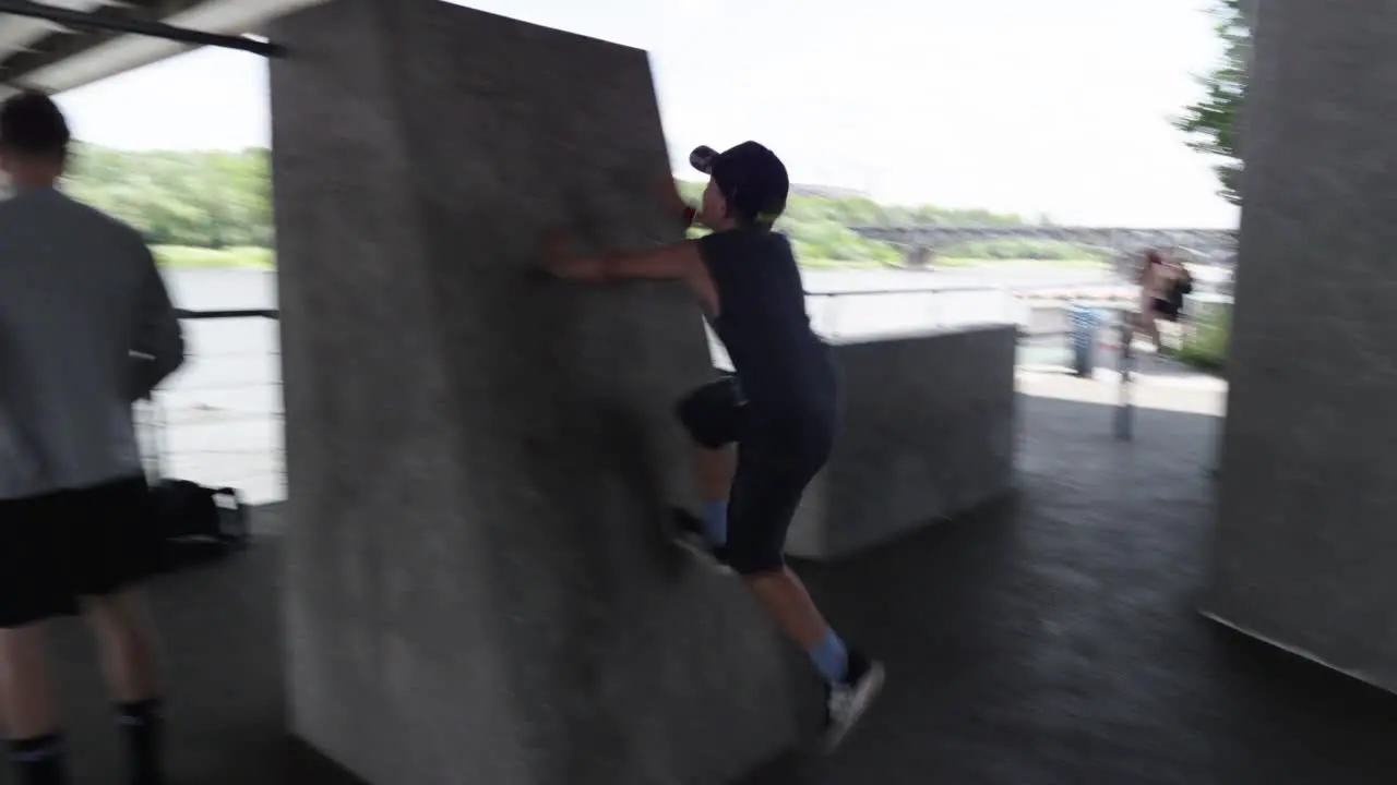 A boy tries to jump onto a concrete block in the outdoor fitness area under the Waršavský Bridge