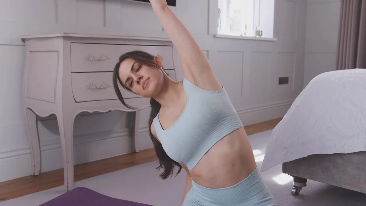 Woman doing yoga joining hands together before stretching sitting on exercise mat in bedroom at home shot in slow motion