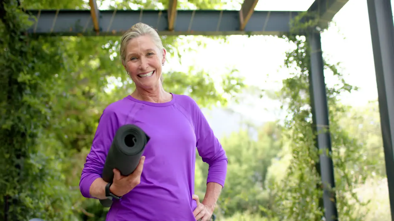 Senior Caucasian woman holding a yoga mat outdoors