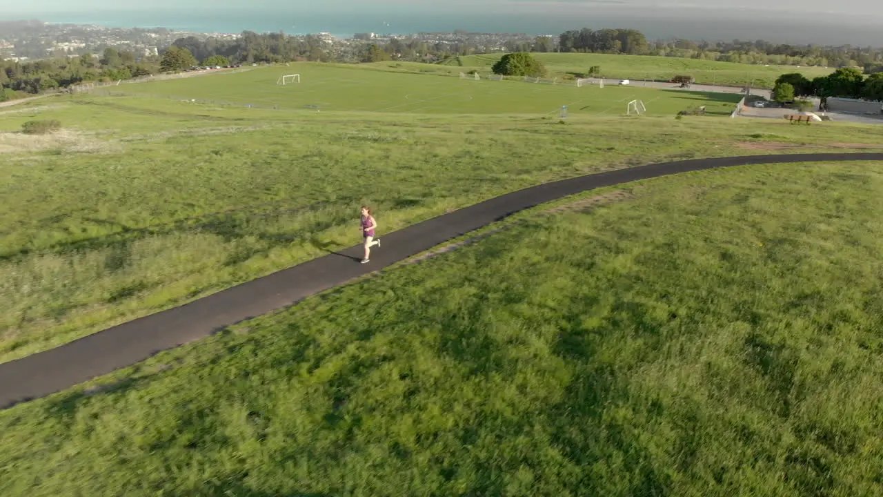 Aerial of Young Woman Running on a Track at Sunset