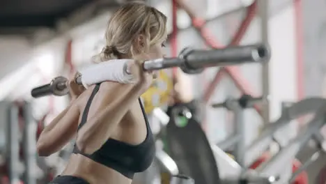 Strong woman doing squat exercise with barbell in fitness center