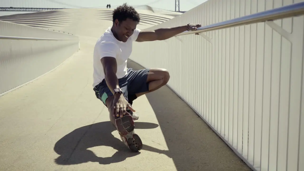 Smiling African American man stretching legs before workout