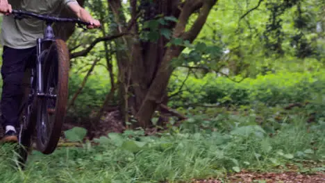 Close Up Slow Motion Shot Of Man On Mountain Bike Cycling Along Trail Through Woodland