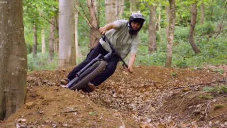 Slow Motion Shot Of Man On Mountain Bike Cycling Along Trail Through Woodland 