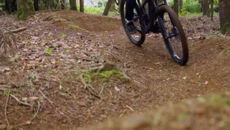 Close Up Slow Motion Of Man On Mountain Bike Cycling Along Dirt Trail Through Woodland