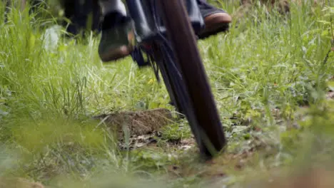 Close Up Of Man On Mountain Bike Cycling Along Grass Trail Through Woodland Towards Camera