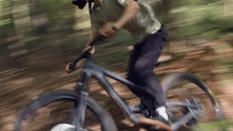 Man On Mountain Bike Cycling Along Dirt Trail Through Woodland At Speed