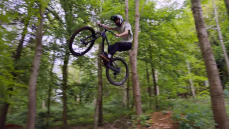 Slow Motion Shot Of Man On Mountain Bike Making Mid Air Jumps On Dirt Trail Through Woodland 8