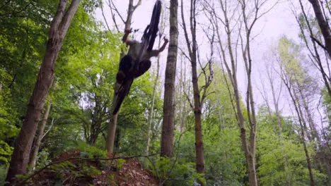 Slow Motion Shot Man On Mountain Bike Making Mid Air Jump On Dirt Trail Through Woodland 3