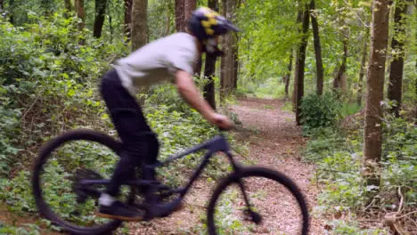 Slow Motion Shot Of Man On Mountain Bike Cycling Along Trail Through Woodland 2