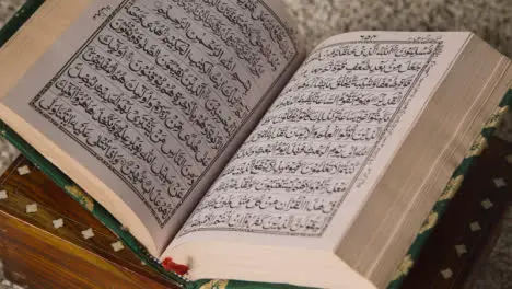 Close Up Of Open Copy Of The Quran On Stand At Home 3