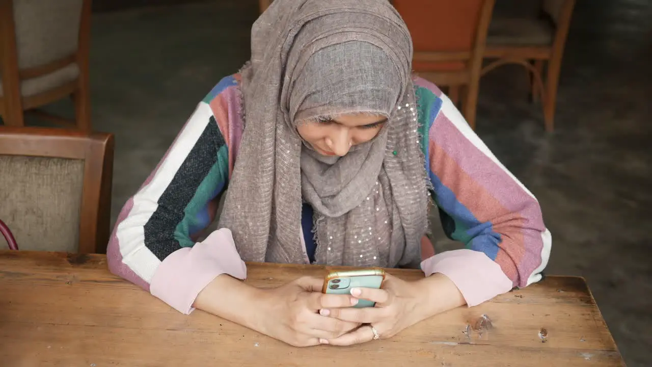 Young muslim women using smart phone at cafe