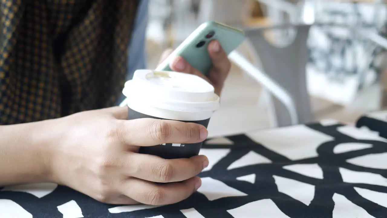 Women hand holding smart phone and paper coffee cup 