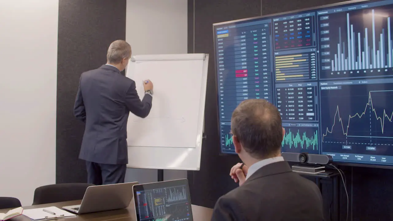 Data Engineer Drawing On Whiteboard In Meeting Room Explaining Data To His Colleague