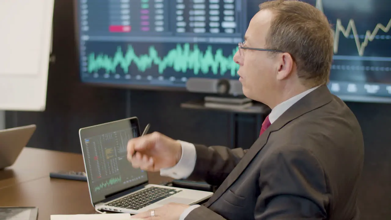 Man Sitting In Monitoring Room And Talking With Colleague