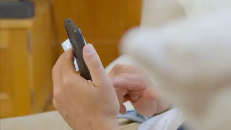 Pull Focus Shot of Middle Aged Man Scrolling On His Smartphone