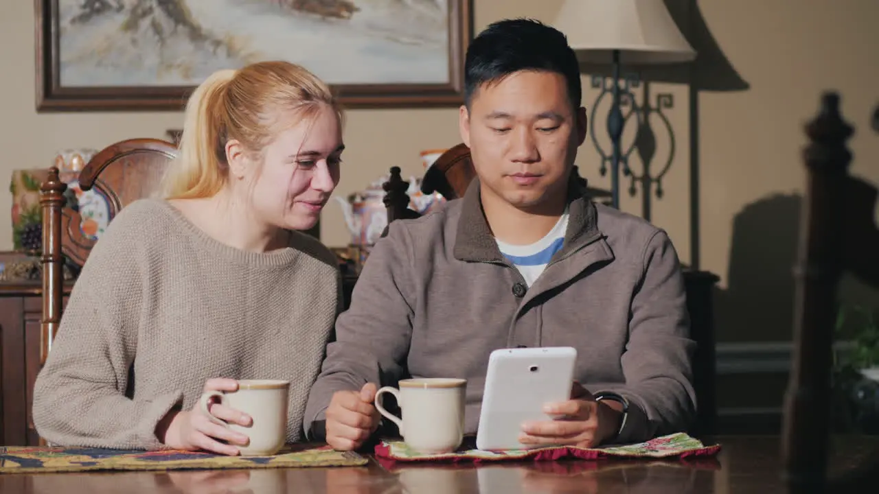 Young Couple Drink Coffee Together Watch The News On A Tablet