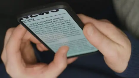 Close Up of Hands Scrolling Coronavirus Vaccine News Article On Phone