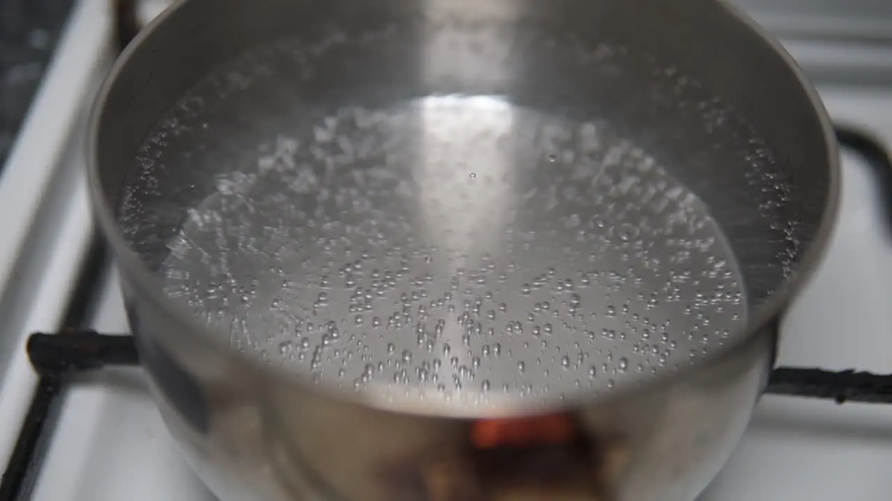 Close up of water bubbles starting to form before boiling in a stainless steel pot on the fire stove