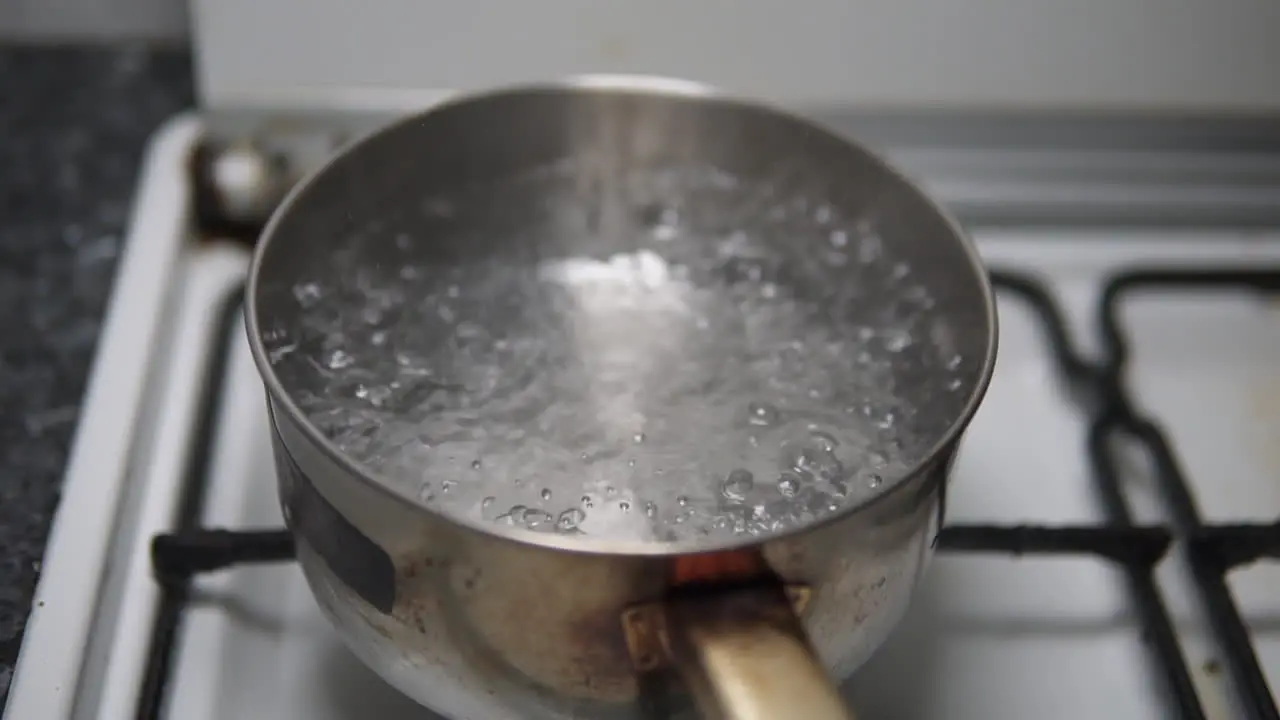 Water boiling in a rusty old stainless steel pot on the fire stove