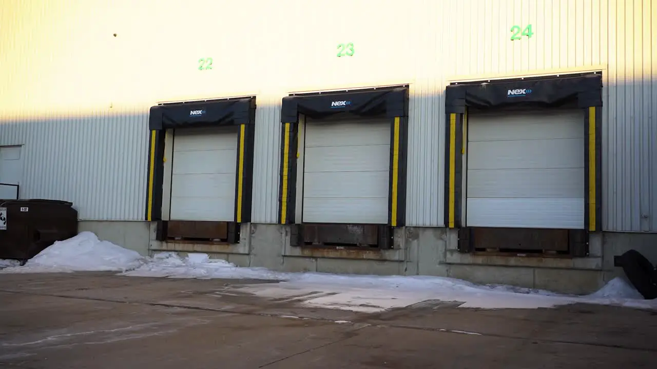 4K Gimbal Daytime Morning Establishing Shot Back Lot Warehouse Distribution Center Loading Bay Doors with Bison Semi Tricks Long Haul Delivery Transportation Supply Chain Vehicles