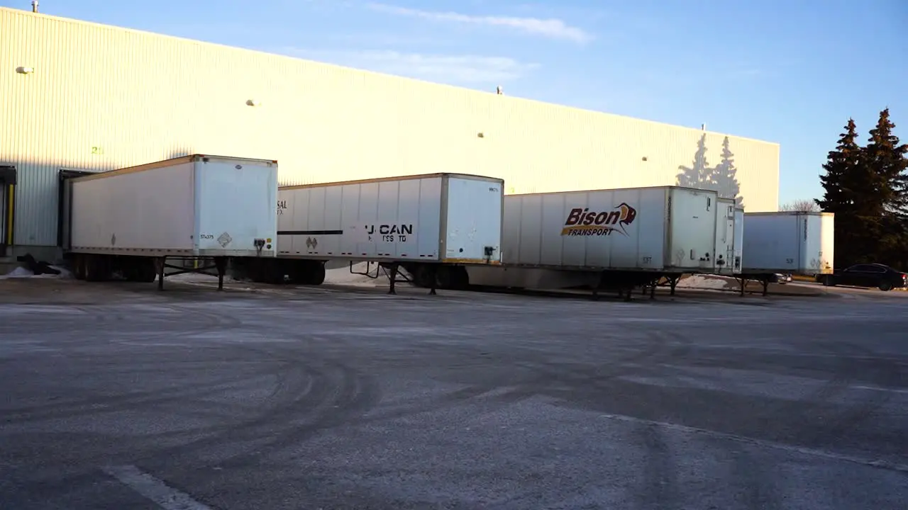 4K Gimbal Daytime Morning Establishing Shot Back Lot Warehouse Distribution Center Loading Bay with Bison Semi Tricks Long Haul Delivery Transportation Supply Chain Vehicles