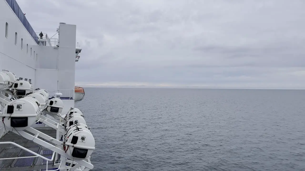 Side of a white car ferry in autopa on the sea with rescue pods attached to the side