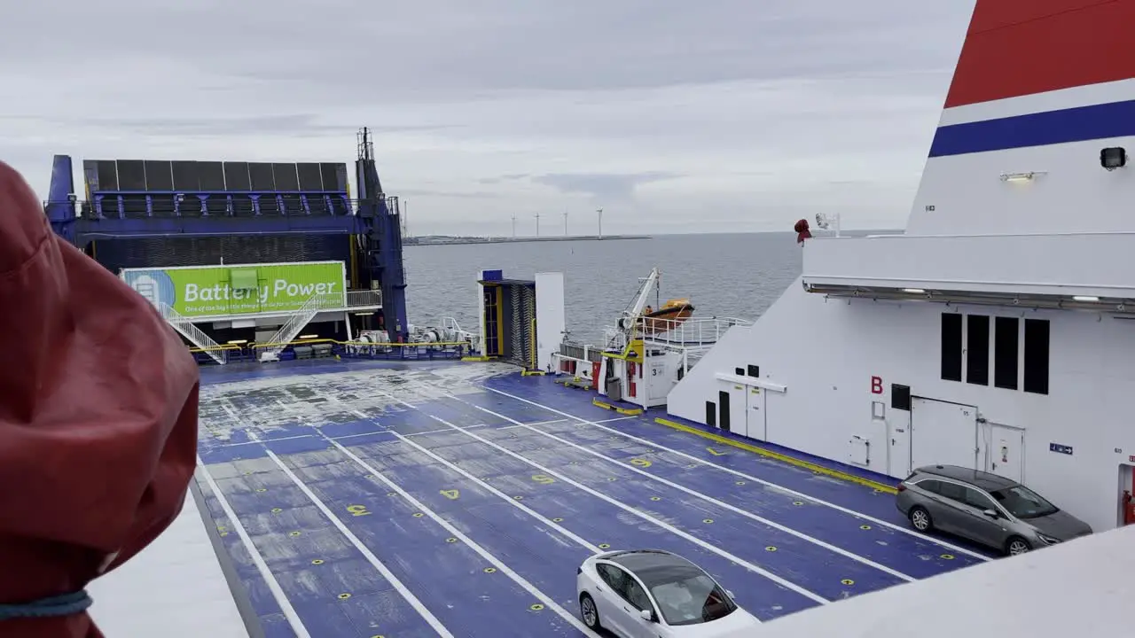 covers a car ferry on the sea with few cars and water to the horizon