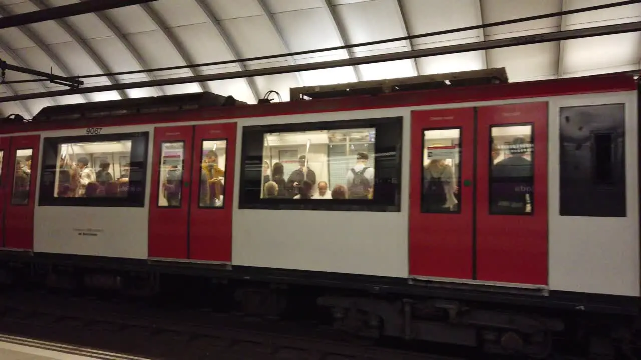 A Red and White Train Wagon Travels the Barcelona Metro Underground Station