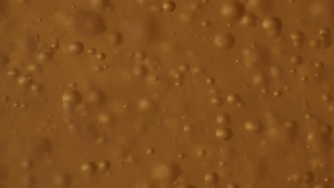 Hundreds of little bubbles floating in orange liquid substance MACRO