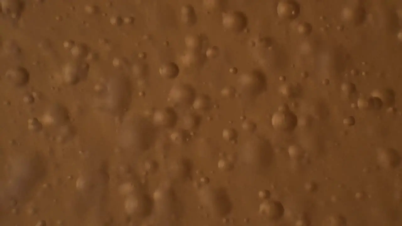 Macro shot of chaotic movement of bubbles floating around in orange liquid