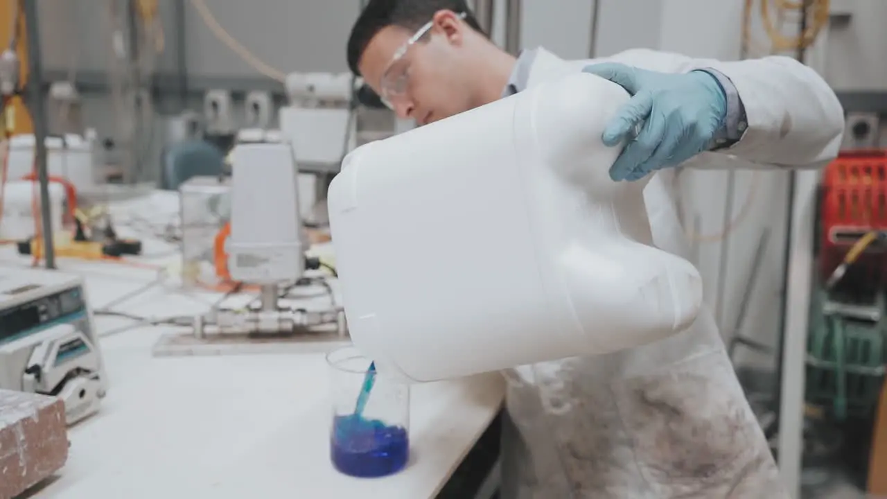 Scientist tipping blue liquid into a beaker in a laboratory