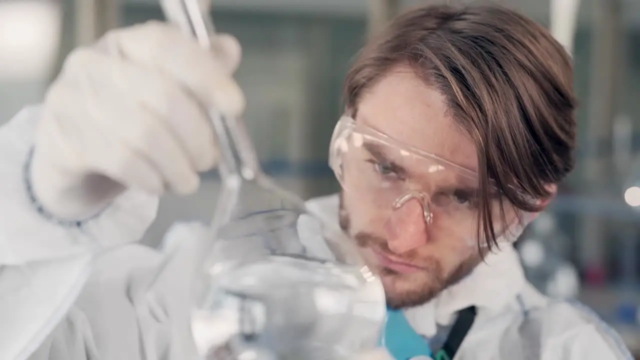 scientist in the laboratory examines a flask with water