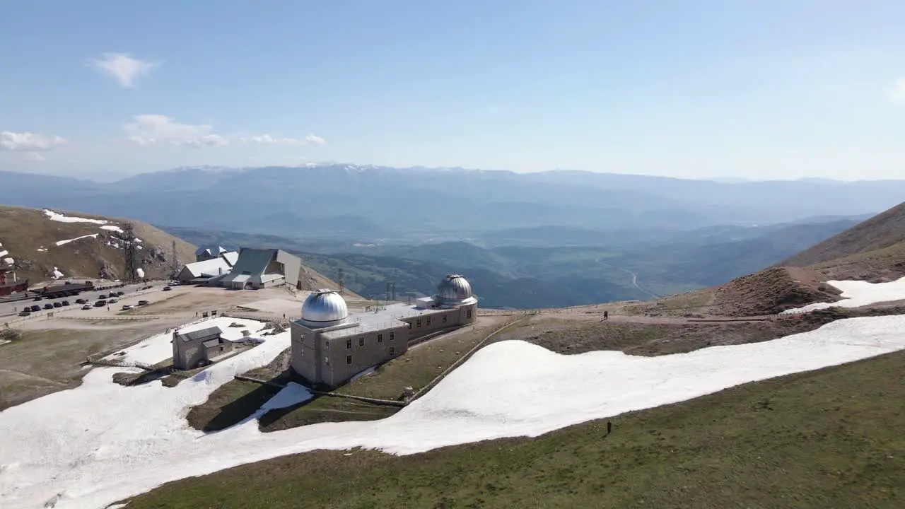 Wide angle drone shot overlooking an observatory located on top of a mountain in a busy ski location in the region of Abruzzo in Italy