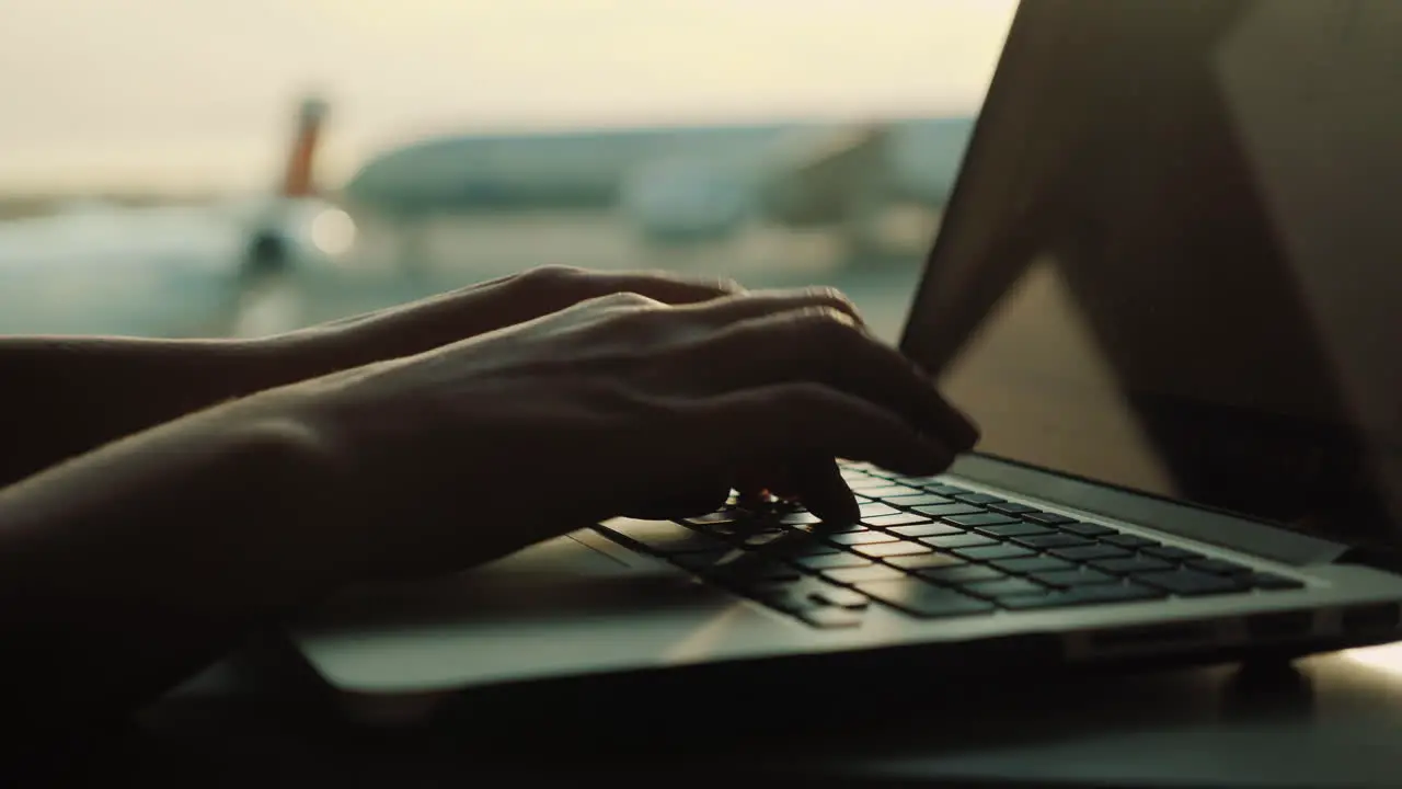 Female Hands Typing On Laptop by Airport Window