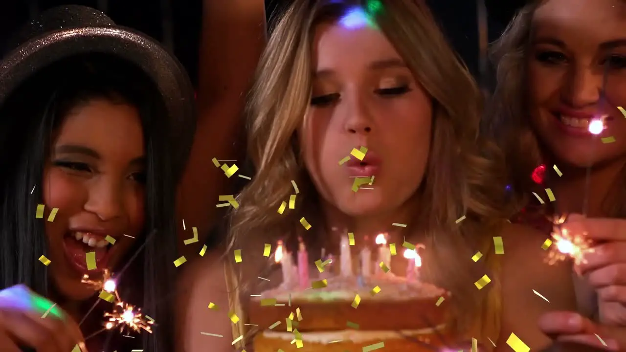 Animation of confetti falling over happy group of friends blowing candles at birthday party