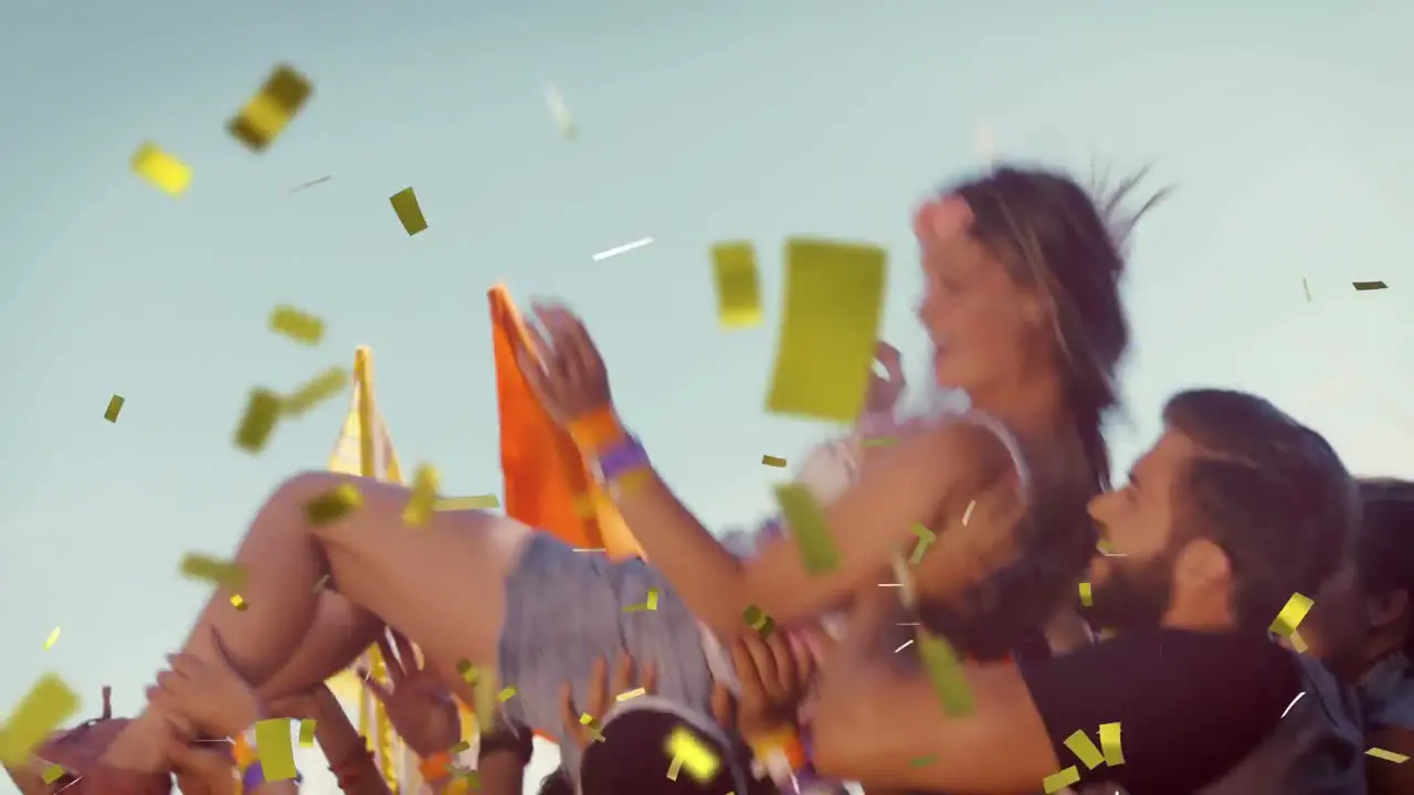 Animation of gold confetti falling over woman being thrown in the air by happy friends outdoors