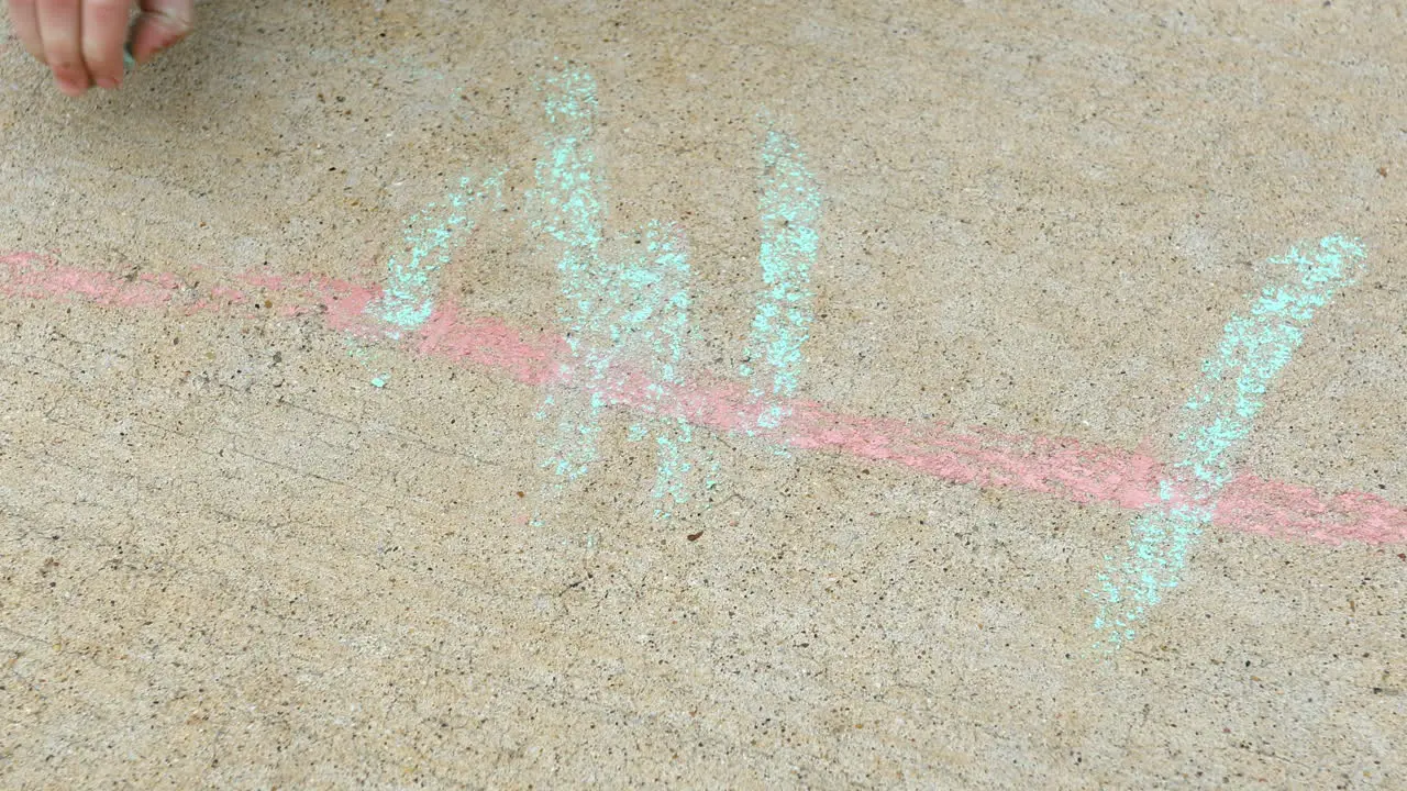 Young boy age 4 years old drawing on sidewalk with chalk