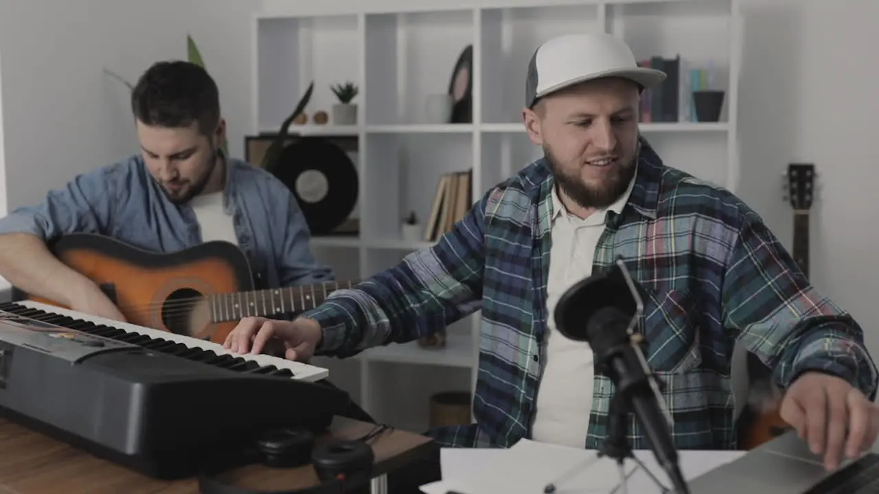 Young Male Musicians Singing And Playing Guitar And Electric Keyboard At Home