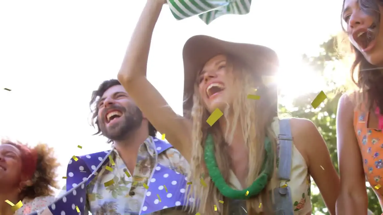 Animation of gold confetti falling over happy people smiling and dancing outdoors