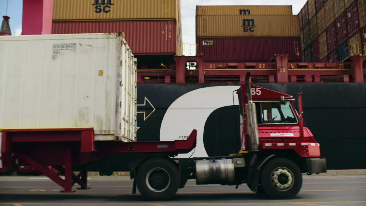 Haulage truck carrying shipping container in Port of Montreal dockyard delivering shipment